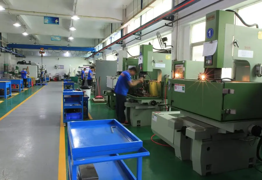 Row of EDM machines on the GY Machining shop floor, an operator at the sinker EDM